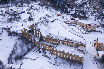 Aerial view of ruins of concentrating factory (late 19th century) in Fasnal village on winter evening. Digoria, North Ossetia, Russia.