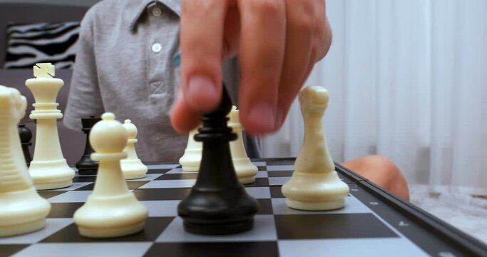 Boy wearing grey tee makes chess turn