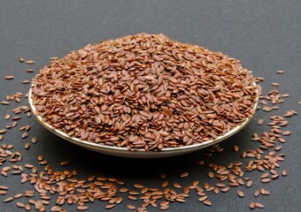 Flax seeds in a plate on black background 