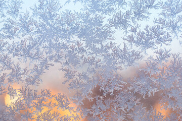 snow frost in the form of natural patterns on the window pane against the background of the morning...