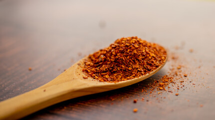Spoon with seasoning chilli  on wooden background. Food background, chilli powder, asian ingredient. 