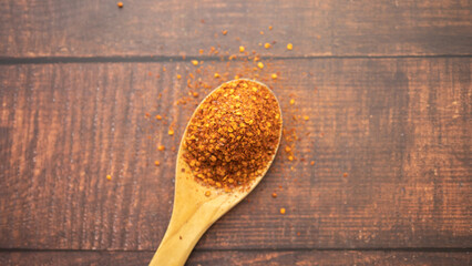 Spoon with seasoning chilli  on wooden background. Food background, chilli powder, asian ingredient. 