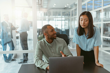 Two multiethnic business colleagues working together in modern office