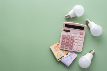 Save energy, accounting and saving money, energy saving light bulbs and notebook on a green background, money spending planning, rising electricity costs, energy crisis in Europe
