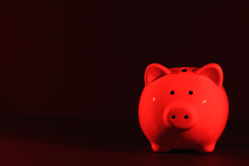 Piggy bank on a dark background with red backlight, copy space. Banking concept. Bright neon lights