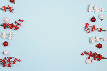 Christmas border of red berries and balls on blue background.