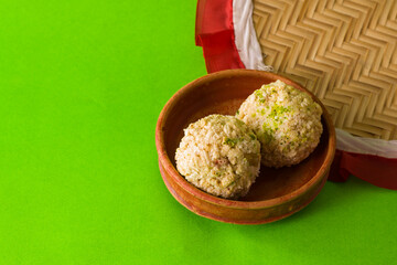 moa, popular bengali dessert is served on a clay plate. this is made of jaggery, puffed rice and made into a ball. famous sweet food in winter season.