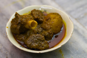 mutton curry and potato served in a bowl. the dish cooked in traditional indian style. spicy red gravy and potato is accompanied.photo taken with selective focus. - obrazy, fototapety, plakaty