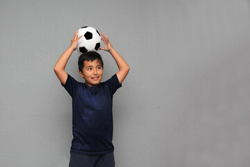 Hispanic Latino 8-year-old boy plays with a soccer ball very excited that he is going to see the...