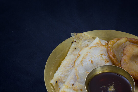 pithe or rice flour dumplings with coconut fillings being served on a plate with date palm jaggery. patishapta or malpoa are traditional bengali foods made during poush sangkranti or makar sankranti.