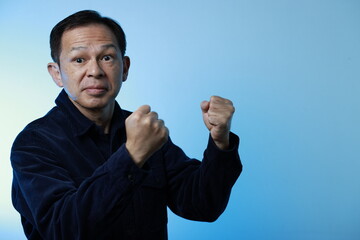 Middle-aged Japanese man in navy blue casual shirt on blue background. Conceptual image of world...