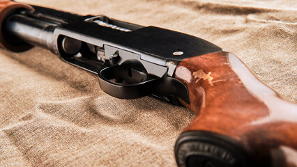a pump-action shotgun lies on a coarse cloth