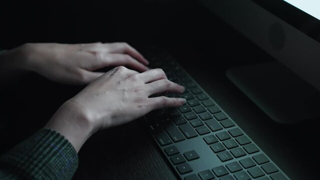 暗い部屋でタイピングする女性