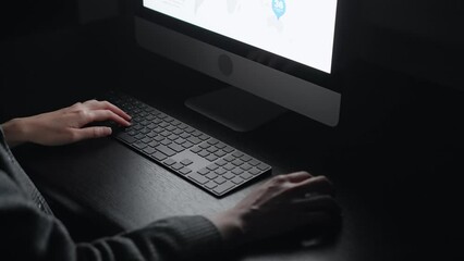 Scene of an anonymous person using a computer in a dark room.