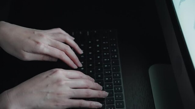 Scene of an anonymous person using a computer in a dark room.