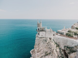 Fototapeta na wymiar Crimea Swallow's Nest Castle on the rock over the Black Sea. It is a tourist attraction of Crimea. Amazing aerial view of the Crimea coast with the castle above abyss on sunny day.