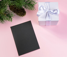 gift box with white silk ribbon fir branch with pine cone and dark card for text .concept...