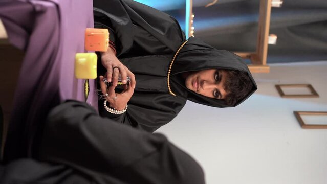 Tarot reading or fortune teller reading tarot cards for his client hands with burning candles and tarot cards on a wooden table.Divination or forecasting concept.
