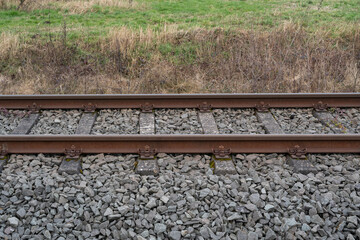 Naklejka premium Rusty railway tracks with gravel stones and concrete sleepers in the countryside