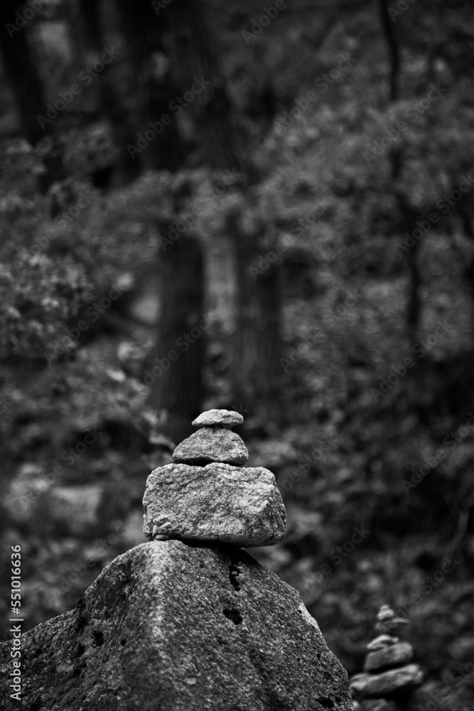 Poster grayscale view of a stack of balanced stones in the wood