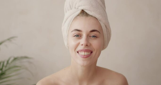 Body treatment. Gorgeous woman wrapped in towel looking camera and shaking head