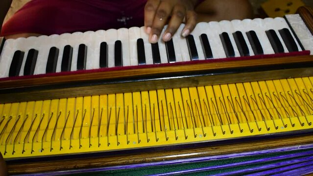 Close up shot of a musician playing Indian traditional musical instrument harmonium.