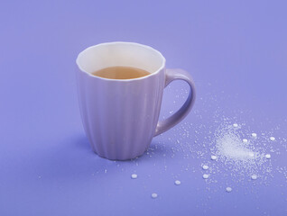 A cup of tea with sweetener and sugar.