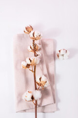 Beige napkin and cotton branch. The concept of natural ecological fabrics.