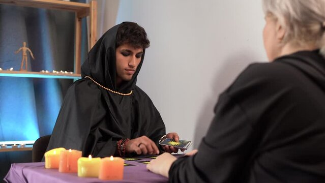 Forecasting.Tarot reader or Fortune teller of hands holding up deck tarot cards. Tarot cards on a table near burning candles.