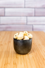 Lotus seeds in a black ceramic bowl on a wooden cutting board