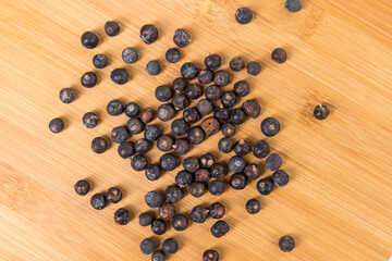 Juniper berries scattered on a wood cutting board top down close up