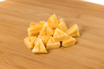 Saffron spiced sugar cubes in a pile on a wood cutting board