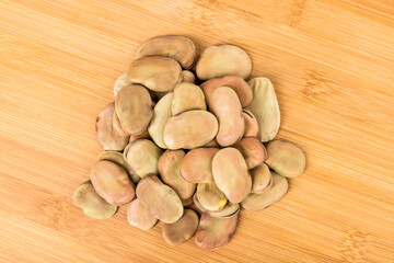 Fava bean heap on a wood cutting board top down view