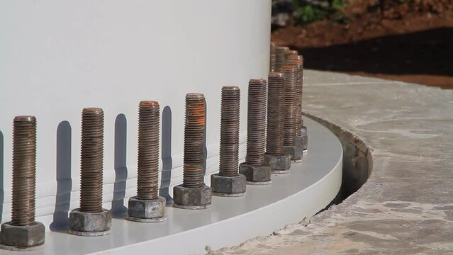 Wind turbine foundation with bolts at the base holding the wind turbine tower structure in place. Construction of a wind farm. Mounting bolts in close-up