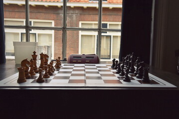 Chess board with dgt clock at a window indoors