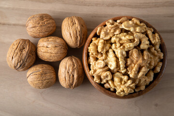 Peeled walnuts and whole walnuts in wooden bowl
