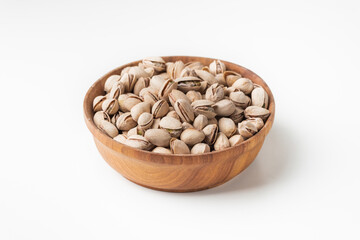 Close up of Pistachio nut seeds in a wooden bowl on the white background. Pistachios in shells. Dried salted beer snack