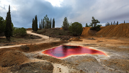 Unrecognizable man walking  near a Lake with red polluted toxic water. Abandoned copper mine