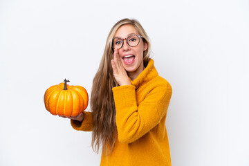 Young blonde woman holding a pumpkin isolated on white background whispering something