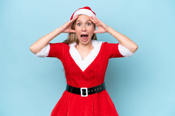 Young blonde woman dressed as mama claus isolated on blue background with surprise expression