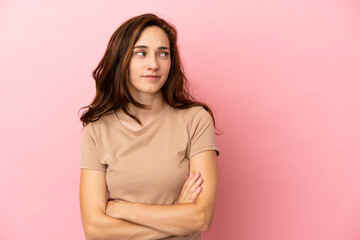 Young caucasian woman isolated on pink background keeping the arms crossed