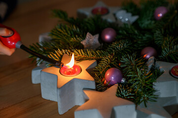 Hand of child lighting a candle on advent wreath on Christmas eve or first advent. Tradtional wreath in Germany. Happy child celebrating family holiday