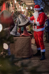 Portrait von einem verkleideten Weihnachtsmann, der auf einem Weihnachtsmarkt von Lichtern umgeben ist