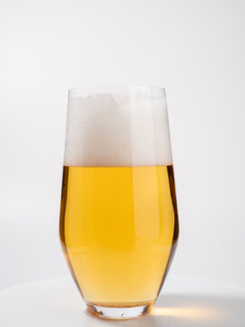 Glass of beer on a white background. A glass of light beer with foam.