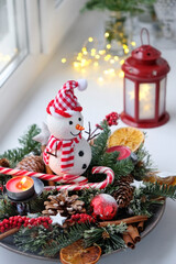 Fototapeta na wymiar Cute snowman and Christmas decorations on table. festive winter season concept. Christmas holiday background. advent time.