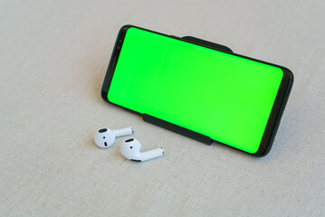Mobile phone and wireless white headphones on table