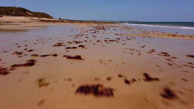 Travelling avant rasant sur une plage couverte de varechs