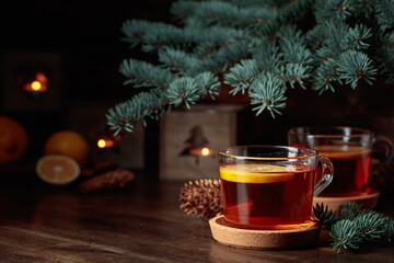 Tea with lemon and small Christmas lanterns on a wooden table.