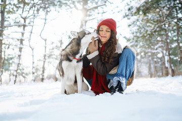 Fototapeta na wymiar Happy woman walking her dog in the winter and both explore the snow together in playful mood. Friendship, pet and human.