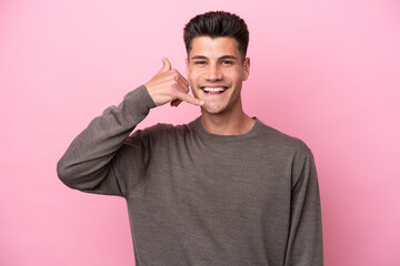 Young caucasian man isolated on pink background making phone gesture. Call me back sign